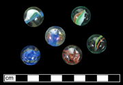 Machine made marbles. Cat eye glass marbles. These marbles have internal strands or ribbons of colors. Cat eye marbles were introduced around 1951 (Randall and Webb 1988:45). Donated to MAC Lab from private collection - click image to see larger view.